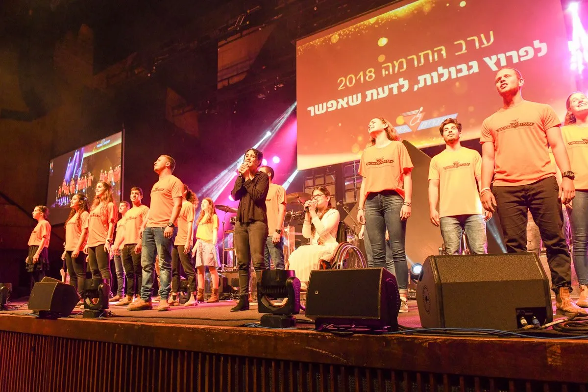 מופיעים וצוות בחולצות כתומות על הבמה בערב התרמה 2018